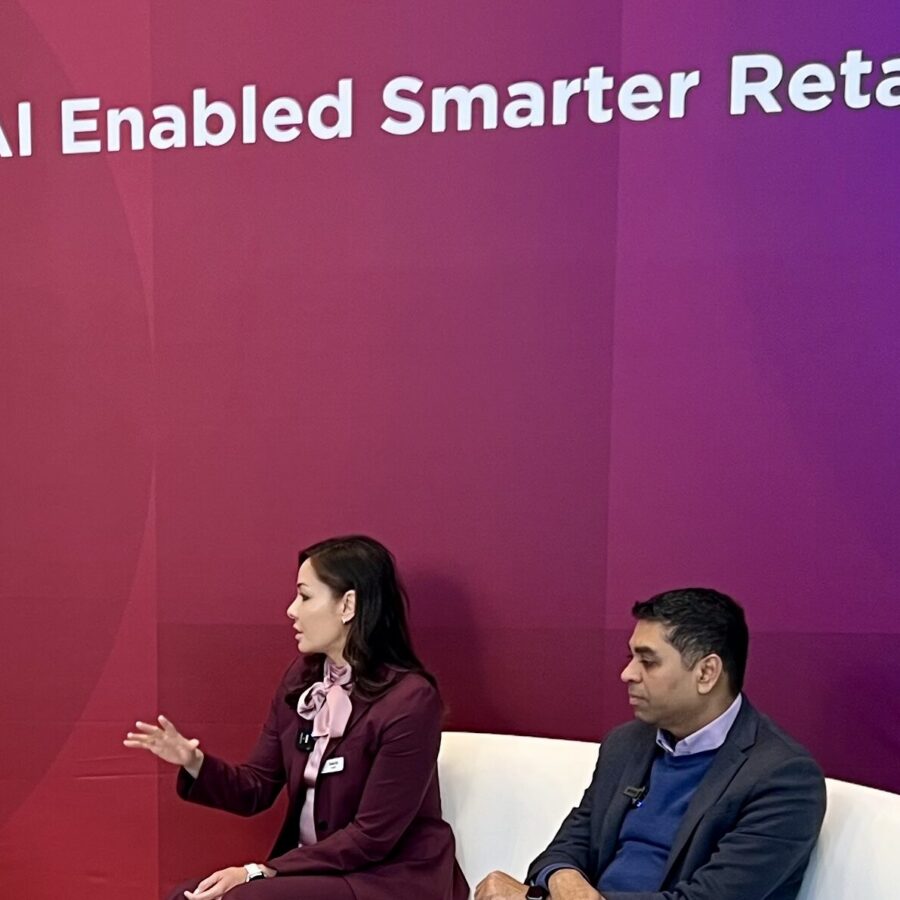 Female AI keynote speaker Susan Sly being interviewed by Lenovo at NRF in front of a backdrop reading AI Enabled Smarter Retail