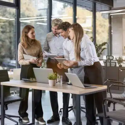 Tech workers collaborating around laptops in a modern office during emotional intelligence training in an AI world